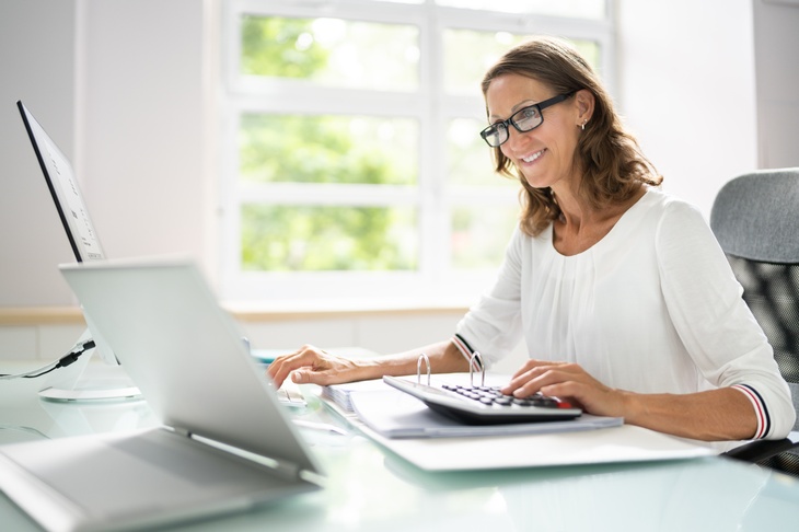 © Andrey Popov | stock.adobe.com Person mit Brille sitzt an einem Schreibtisch und arbeitet mit einem Laptop